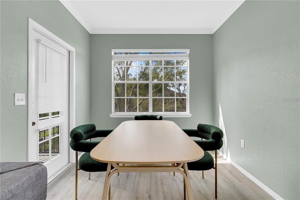 A dining room features a light wood table, four dark green chairs, and a large window — 2632 ROBERT TRENT JONES DRIVE UNIT 136, ORLANDO, FL