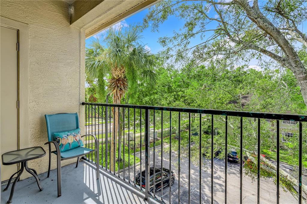 A balcony with a metal railing overlooks a parking lot, trees, and a palm tree — 2632 ROBERT TRENT JONES DRIVE UNIT 136, ORLANDO, FL