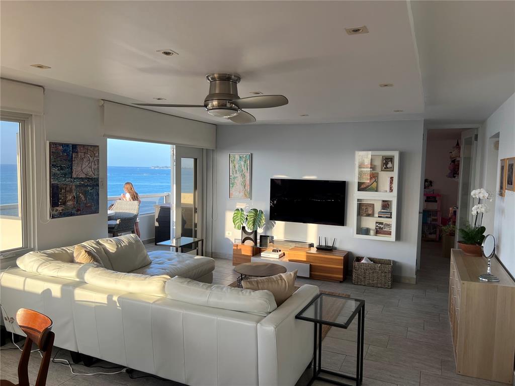 A living room with a white sectional sofa, a wall-mounted television, and an ocean view — 4939 ISLA VERDE AVENUE UNIT 801, CAROLINA, PR