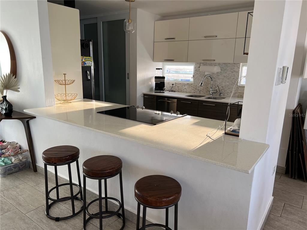 A kitchen features a white quartz breakfast bar, dark wood stools, and modern cabinetry — 4939 ISLA VERDE AVENUE UNIT 801, CAROLINA, PR