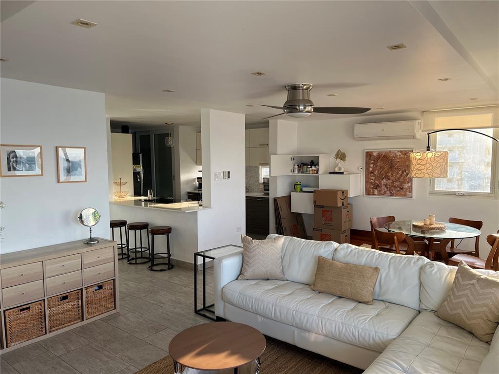 A living room with a white sectional sofa, dining area, and kitchen with bar seating — 4939 ISLA VERDE AVENUE UNIT 801, CAROLINA, PR