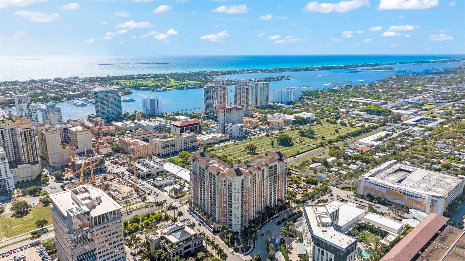 An aerial view shows high-rise buildings, a cemetery, and a coastal waterway under a blue sky — 550 Okeechobee Boulevard # 1609, West Palm Beach FL 33401, WEST PALM BEACH, FL