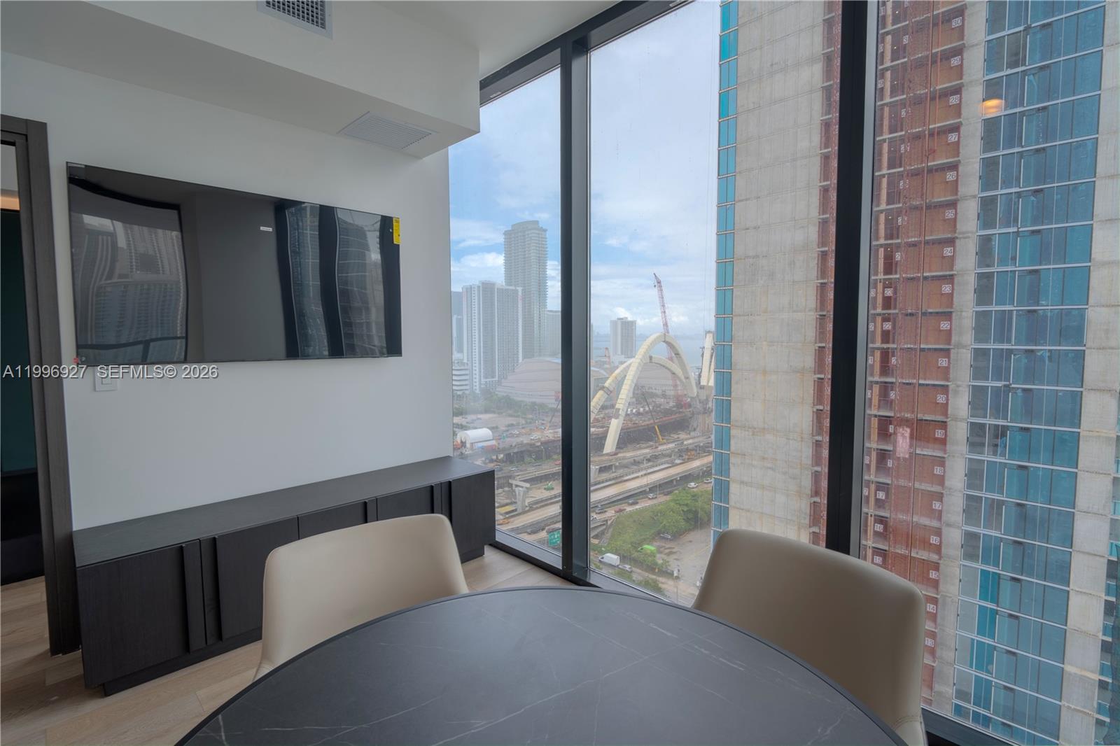 A dining area features a round table, two chairs, and a view of city construction — 20 NE 11th st # 2308, Miami FL 33132, MIAMI, FL