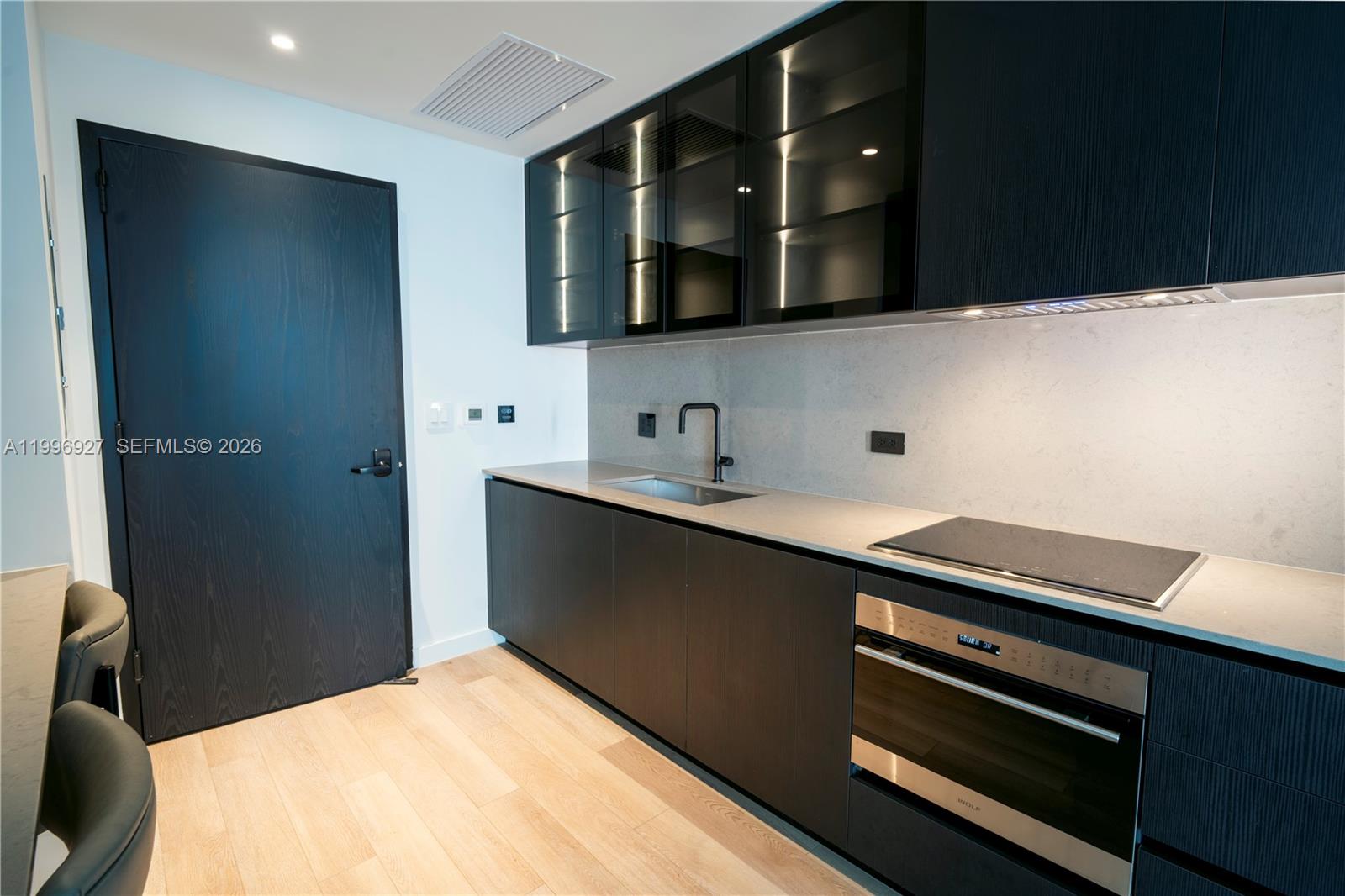 A modern kitchen features dark wood cabinetry, a stainless steel oven, and light stone countertops — 20 NE 11th st # 2308, Miami FL 33132, MIAMI, FL