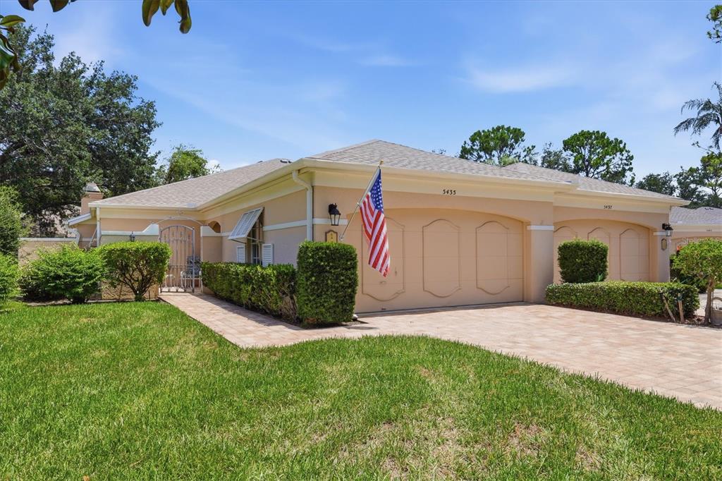 A single-story peach-colored house with a paved driveway, a garage, and a front lawn — 5435 CHANTECLAIRE UNIT 69, SARASOTA, FL