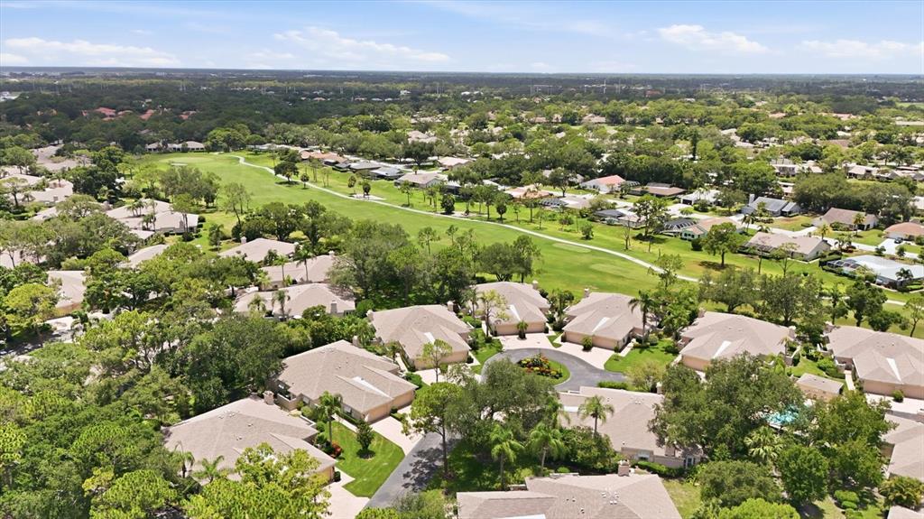 An aerial view shows a residential neighborhood with tan houses bordering a green golf course — 5435 CHANTECLAIRE UNIT 69, SARASOTA, FL