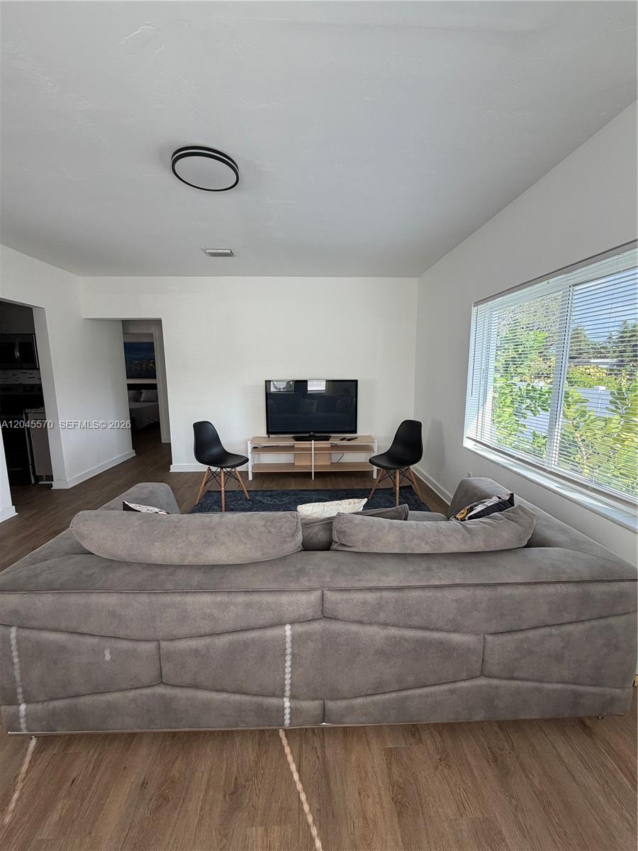 A living room features a large gray sofa, two black chairs, and a television stand — 1215 NE 109th St # 1215, Miami FL 33161, MIAMI, FL