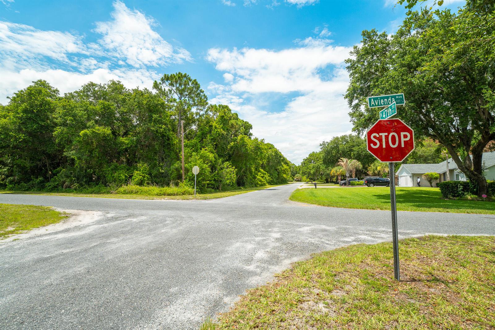 A stop sign stands at a rural intersection with a paved road and lush trees — 47 N St, Fort Pierce FL 34946, FORT PIERCE, FL