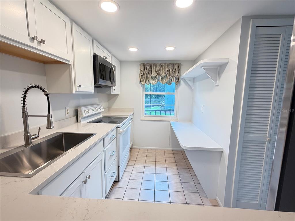 A white kitchen features a stainless steel sink, white cabinets, and a window with valance — 333 LAKE HOWARD DRIVE NW UNIT 211B, WINTER HAVEN, FL