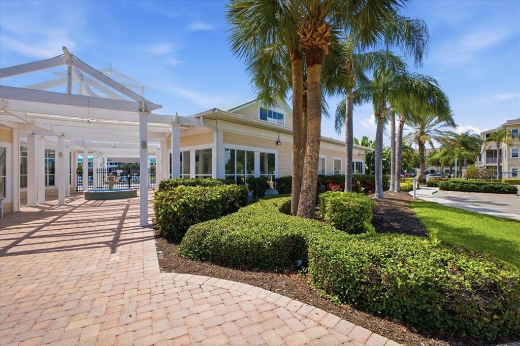 A paved walkway leads to a building entrance with a white pergola and palm trees — 4802 51ST STREET W UNIT 903, BRADENTON, FL