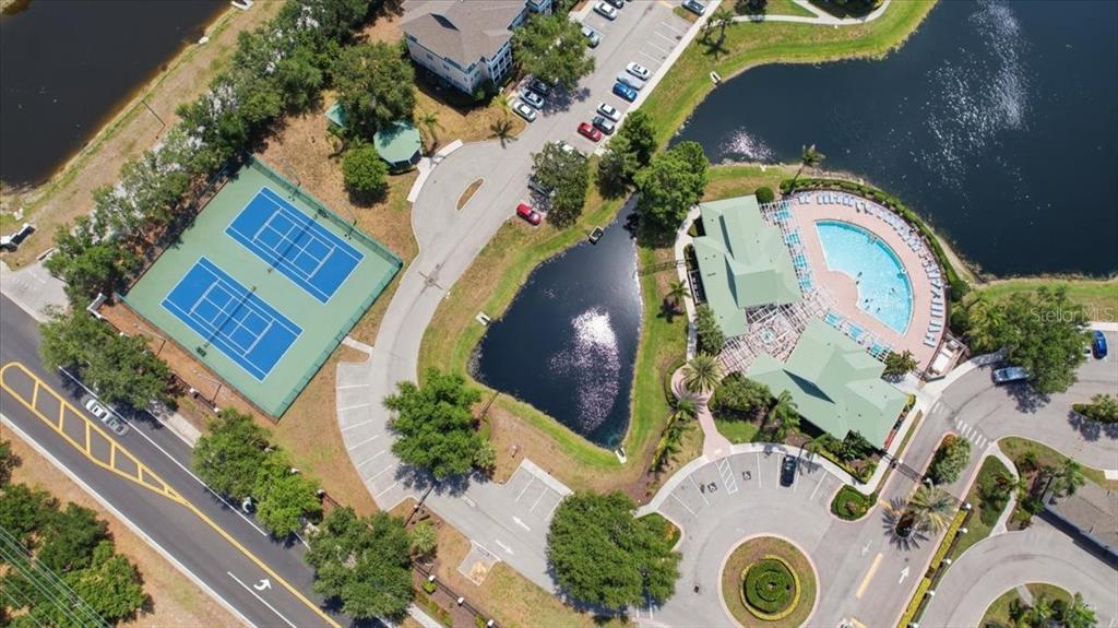 An aerial view shows a community complex with tennis courts, a pool, and a pond — 4802 51ST STREET W UNIT 903, BRADENTON, FL