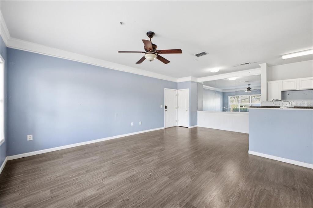 A spacious living room features light blue walls, wood-look flooring, and a ceiling fan — 4802 51ST STREET W UNIT 903, BRADENTON, FL