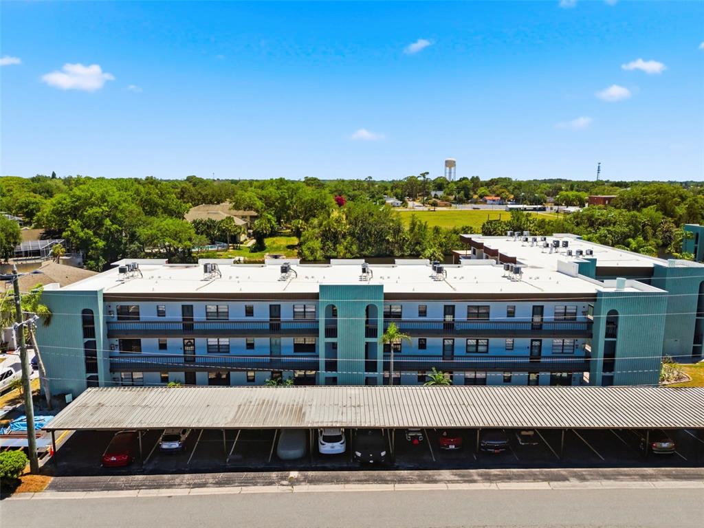An aerial view shows a multi-story apartment building with a covered parking area in front — 5640 FERGUSON COURT UNIT 2208, NEW PORT RICHEY, FL