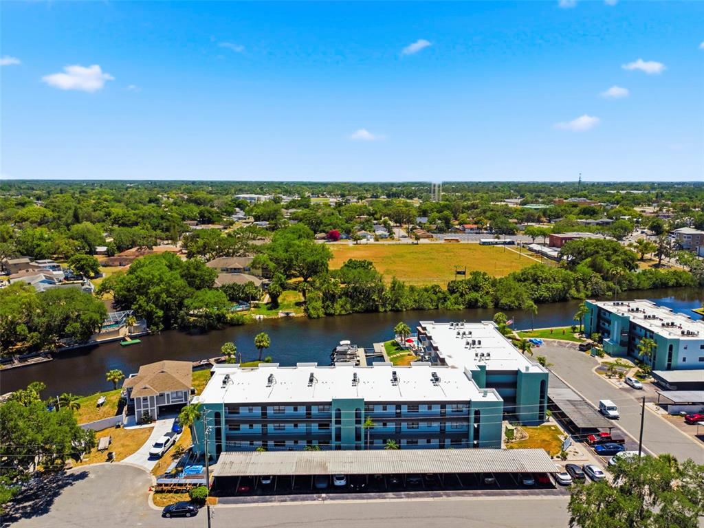 An aerial view shows a multi-story apartment building with a covered parking area and canal — 5640 FERGUSON COURT UNIT 2208, NEW PORT RICHEY, FL