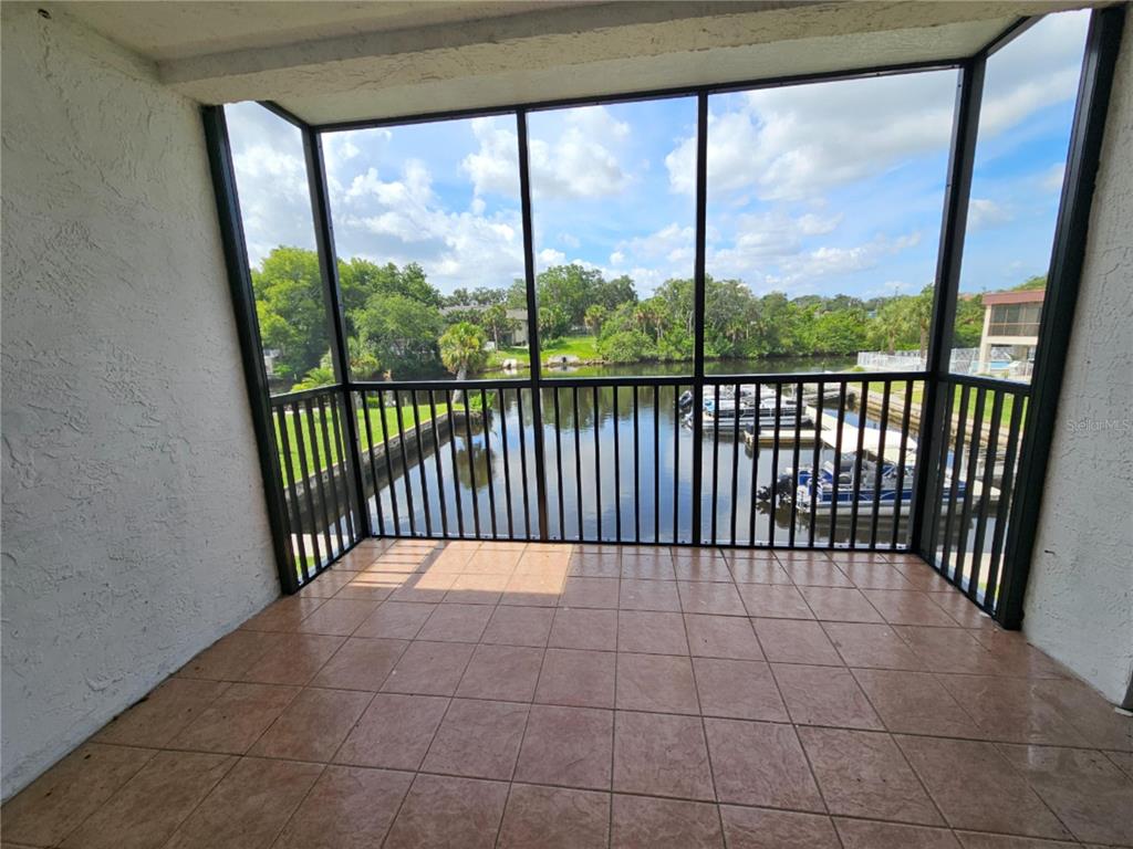 A screened-in balcony with tiled flooring overlooks a canal with docked boats — 5640 FERGUSON COURT UNIT 2208, NEW PORT RICHEY, FL
