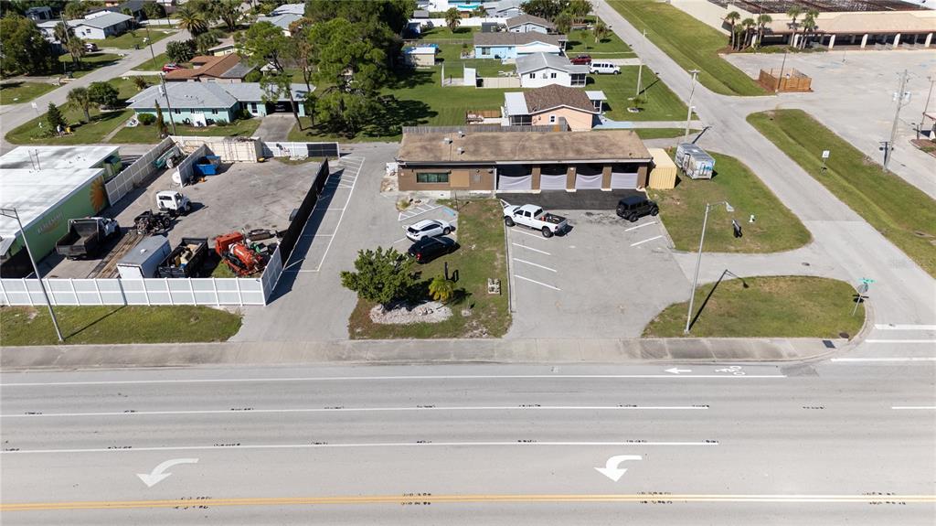 An aerial view shows a commercial building with a parking lot and fenced storage area — 334 S INDIANA AVENUE, ENGLEWOOD, FL