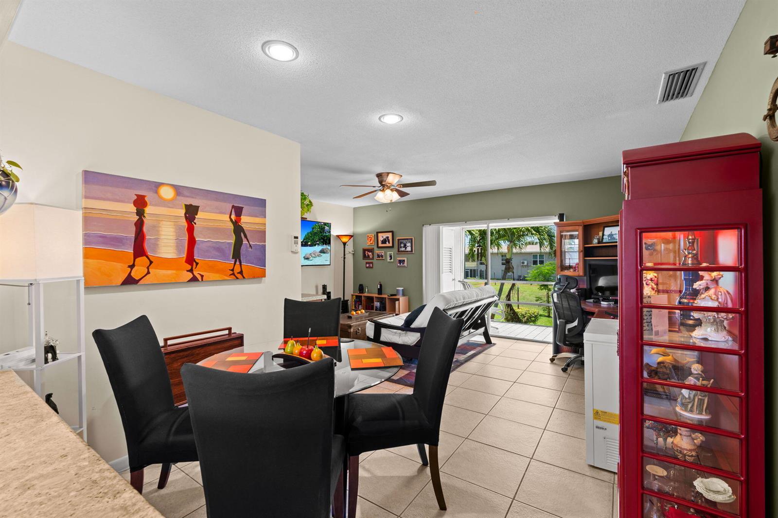 A dining area with a glass table and black chairs opens into a living room — 312 NE 17th Avenue # 203, Boynton Beach FL 33435, BOYNTON BEACH, FL