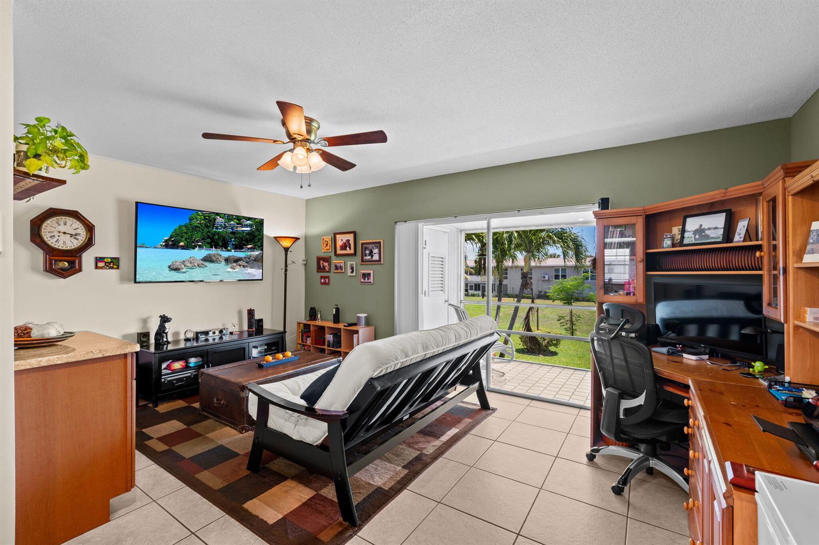 A living room with a futon, television, desk, and sliding glass doors leading to a patio — 312 NE 17th Avenue # 203, Boynton Beach FL 33435, BOYNTON BEACH, FL