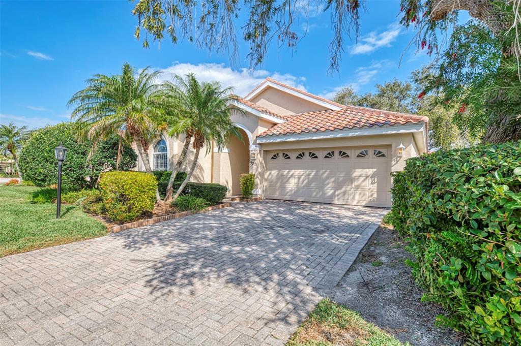 A single-story house with a tiled roof, a brick paver driveway, and palm trees — 5271 HIGHBURY CIRCLE, SARASOTA, FL