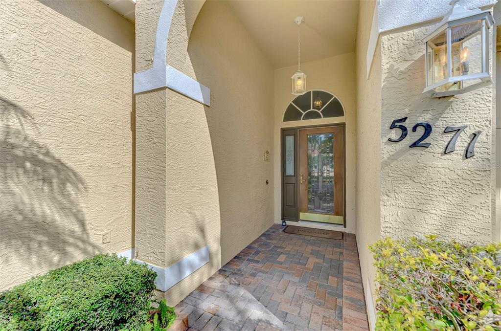 A paved walkway leads to a front door with a glass insert and arched transom — 5271 HIGHBURY CIRCLE, SARASOTA, FL