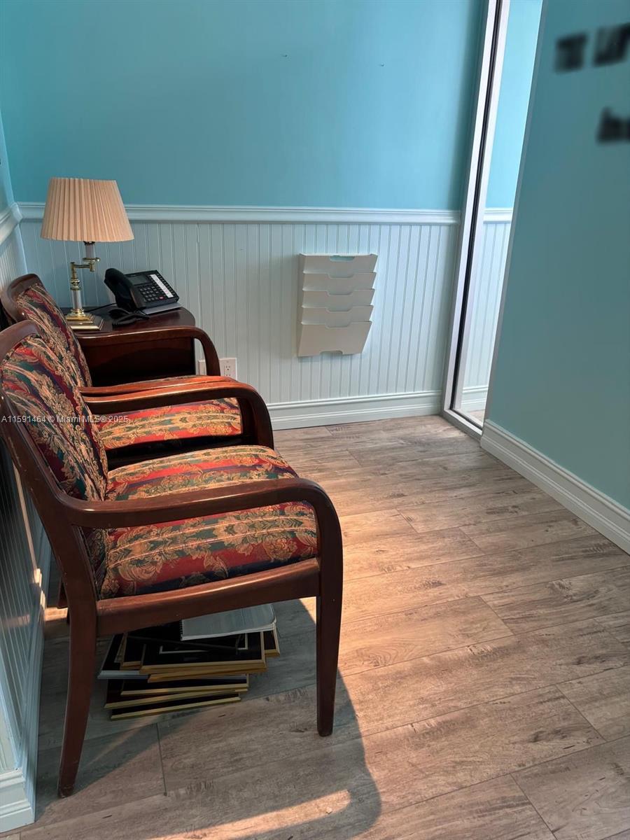 A small office area features two patterned armchairs, a side table with a lamp, and beadboard paneling — 1720 Harrison St # 8C, Hollywood FL 33020, HOLLYWOOD, FL