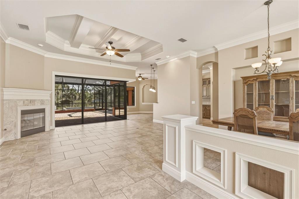 A spacious living and dining area features tile floors, a coffered ceiling, and a fireplace — 3000 NARCISSUS TERRACE, NORTH PORT, FL