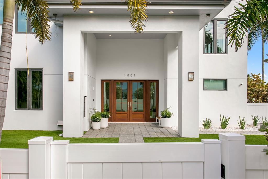 A modern white house exterior features a covered entryway with wooden double doors — 1801 PASS A GRILLE WAY, ST PETE BEACH, FL