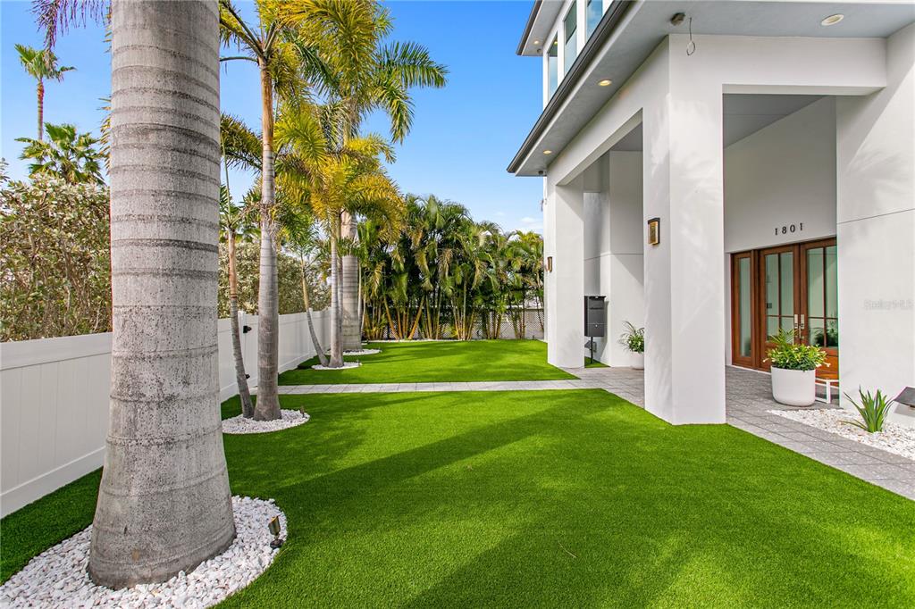 A modern living room features a curved blue sofa, floor-to-ceiling windows, and waterfront views — 1801 PASS A GRILLE WAY, ST PETE BEACH, FL