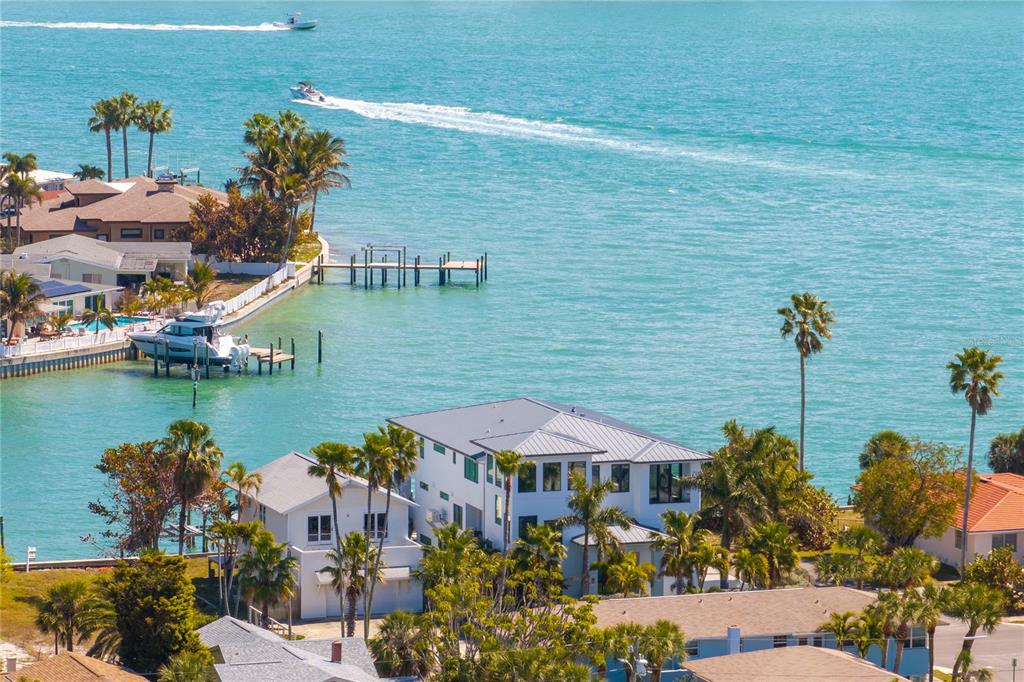 A white house exterior features a green artificial turf lawn and several palm trees — 1801 PASS A GRILLE WAY, ST PETE BEACH, FL