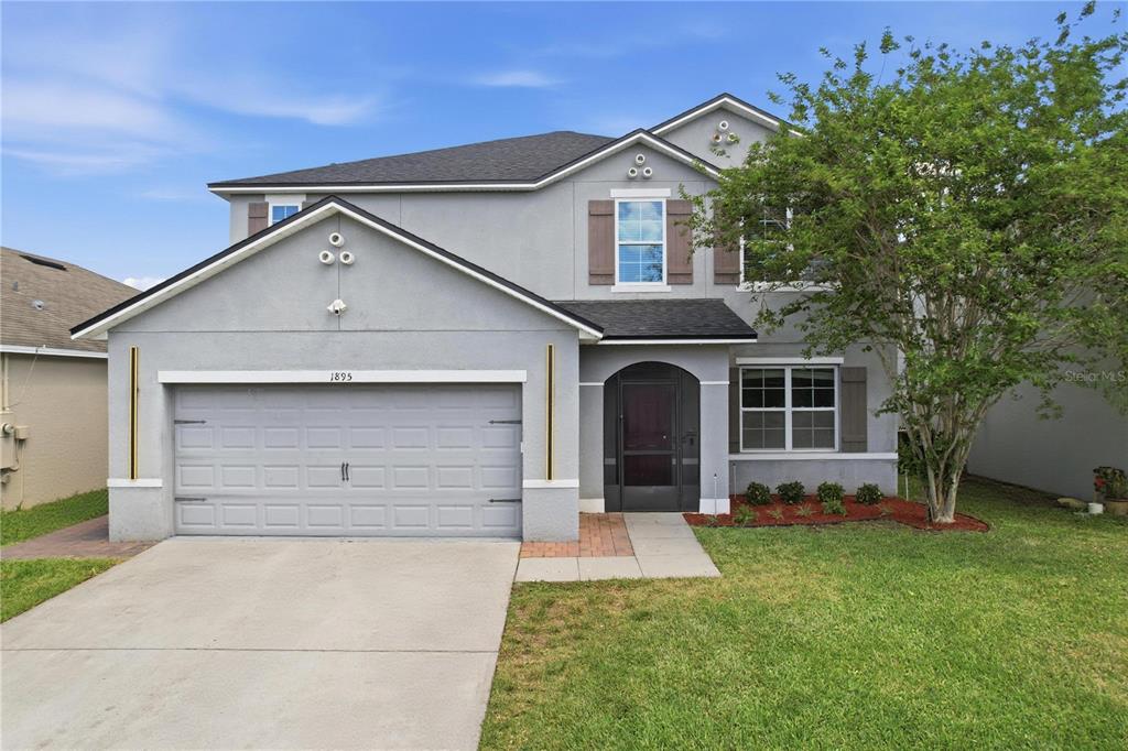 A two-story gray house with a two-car garage and a front yard with a tree — 1895 GREEN DRAGON DRIVE, ST CLOUD, FL