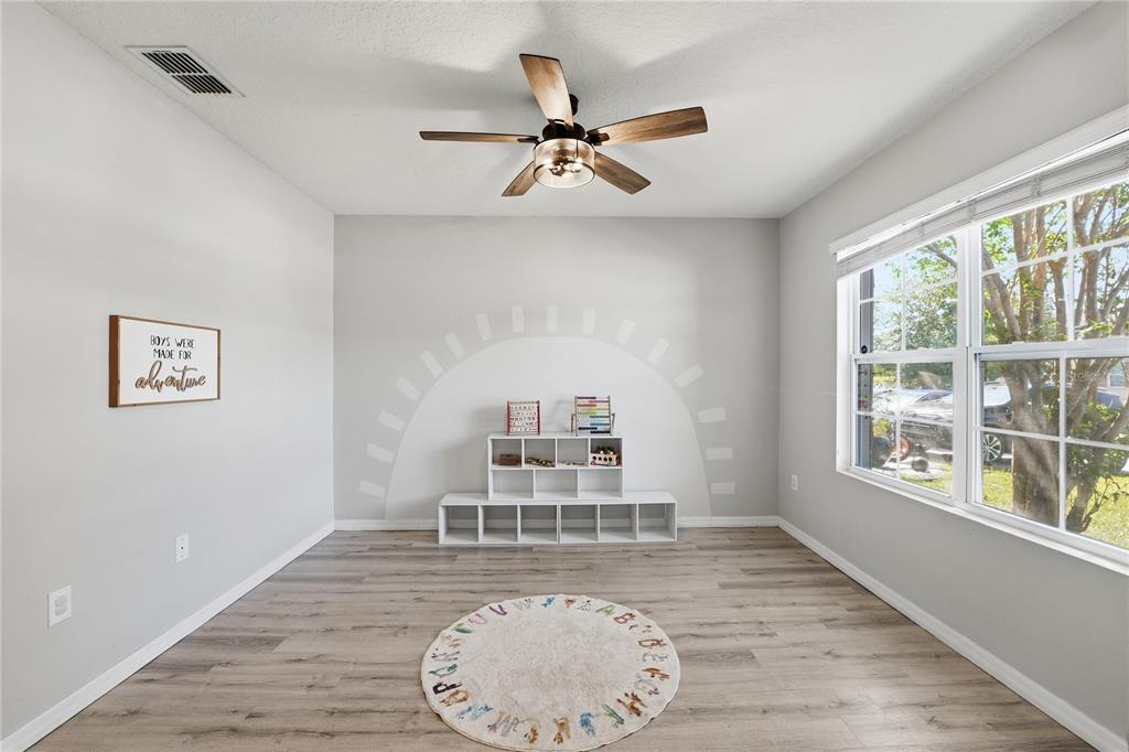 A playroom with light gray walls, wood-look flooring, a ceiling fan, and a white storage unit — 1895 GREEN DRAGON DRIVE, ST CLOUD, FL