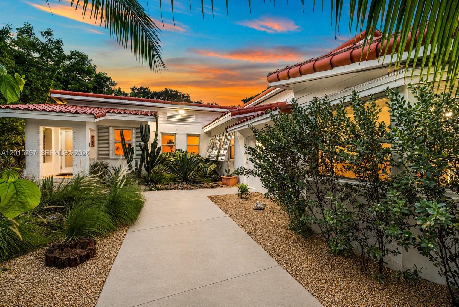 A concrete walkway leads to the entrance of a white house with a tile roof — 723 NE 112th St, Biscayne Park FL 33161, BISCAYNE PARK, FL