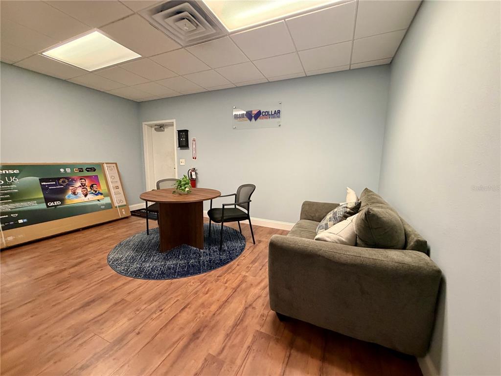 An office waiting area features a sofa, a round table with chairs, and wood flooring — 2422 DESTINY WAY, ODESSA, FL