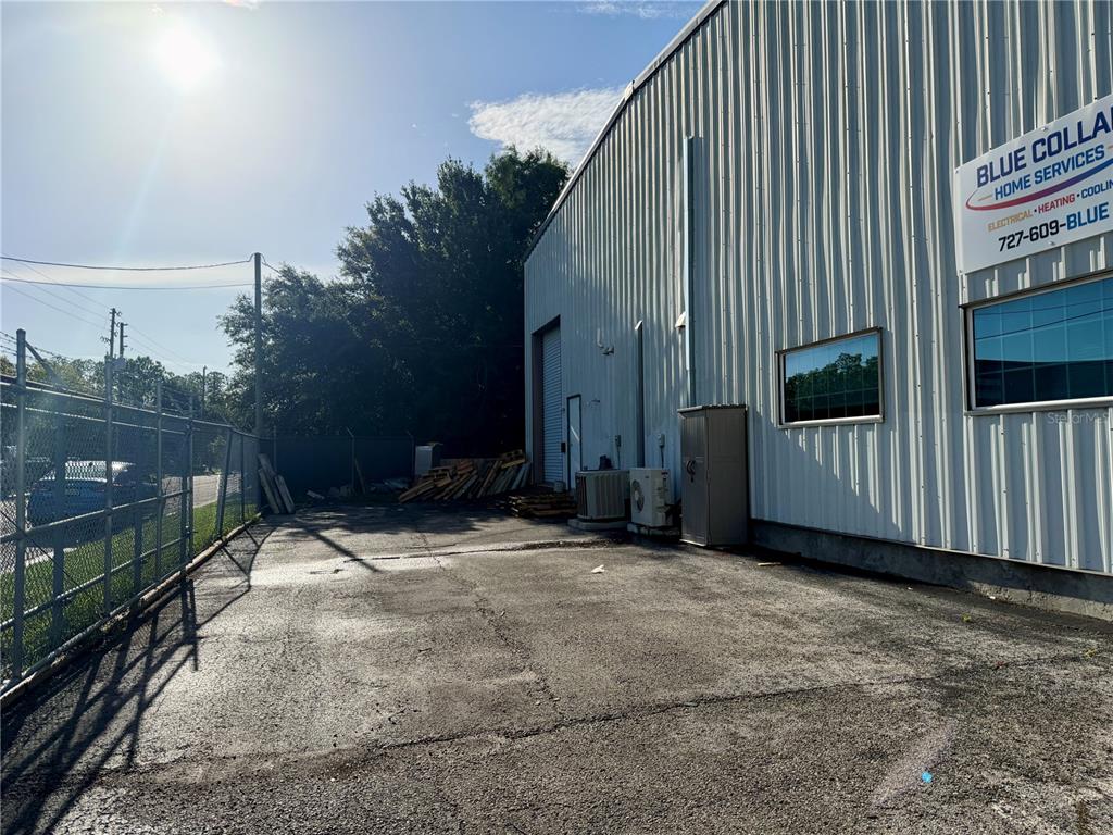 An exterior view shows the side of a metal warehouse building with a paved lot — 2422 DESTINY WAY, ODESSA, FL