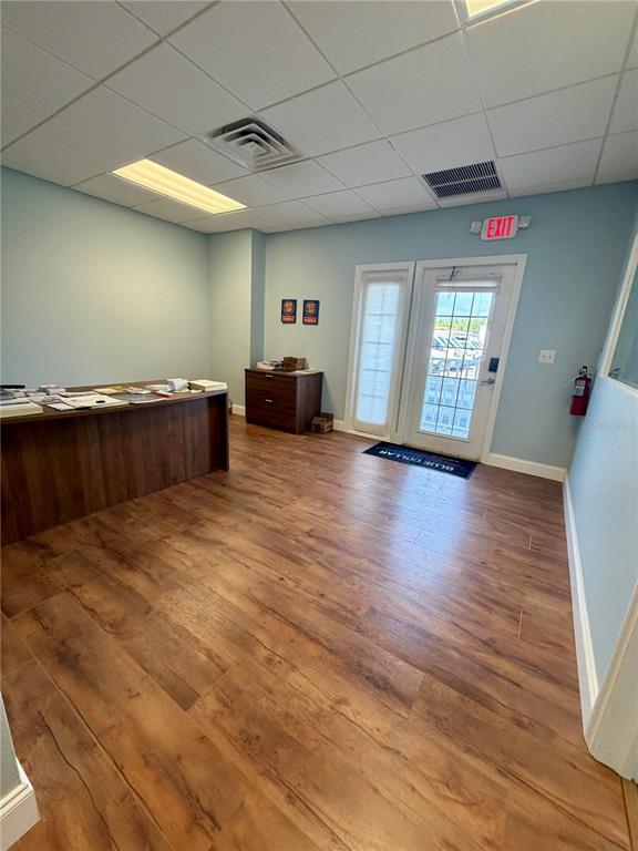 An office space features wood-look flooring, a dark wood desk, and a glass-paneled exterior door — 2422 DESTINY WAY, ODESSA, FL