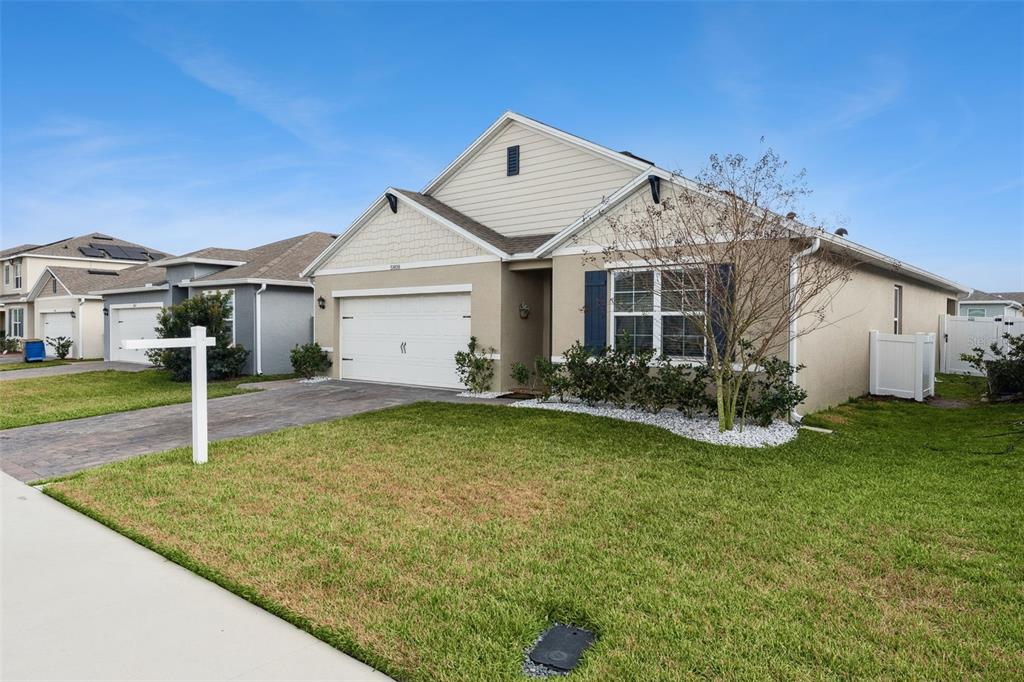 A single-story suburban house with a two-car garage, beige stucco siding, and a front lawn — 5808 ARBORETUM STREET, ST CLOUD, FL