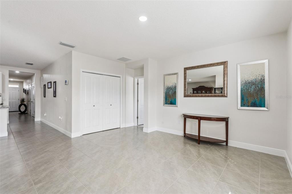 A bright, tiled entryway features a console table, wall art, a mirror, and closet doors — 5808 ARBORETUM STREET, ST CLOUD, FL