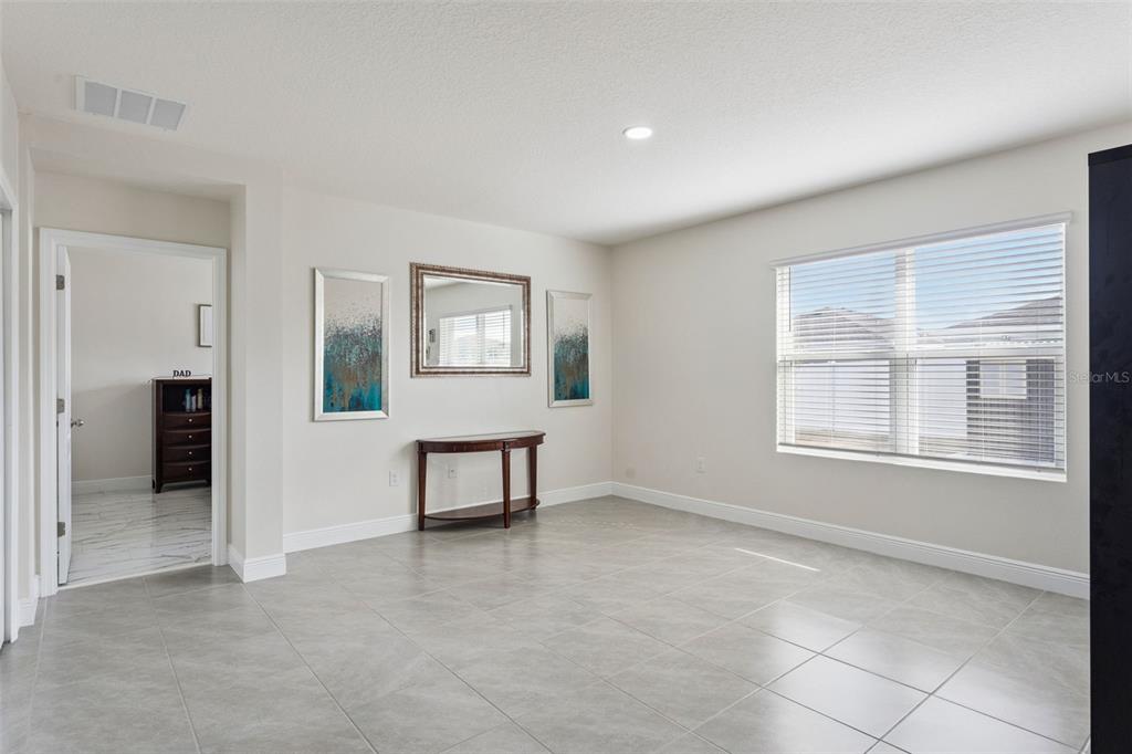 A room with light-colored walls, gray tile flooring, a console table, and a large window — 5808 ARBORETUM STREET, ST CLOUD, FL