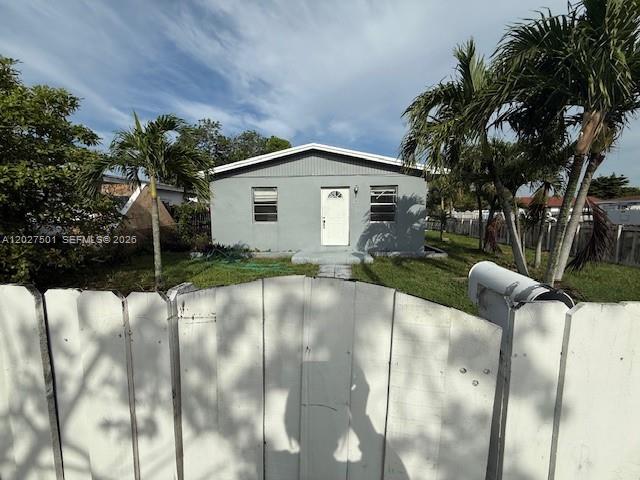 A gray, single-story house is viewed from behind a white wooden picket fence — 3700 SW 56TH AVE # 3700, West Park FL 33023, WEST PARK, FL
