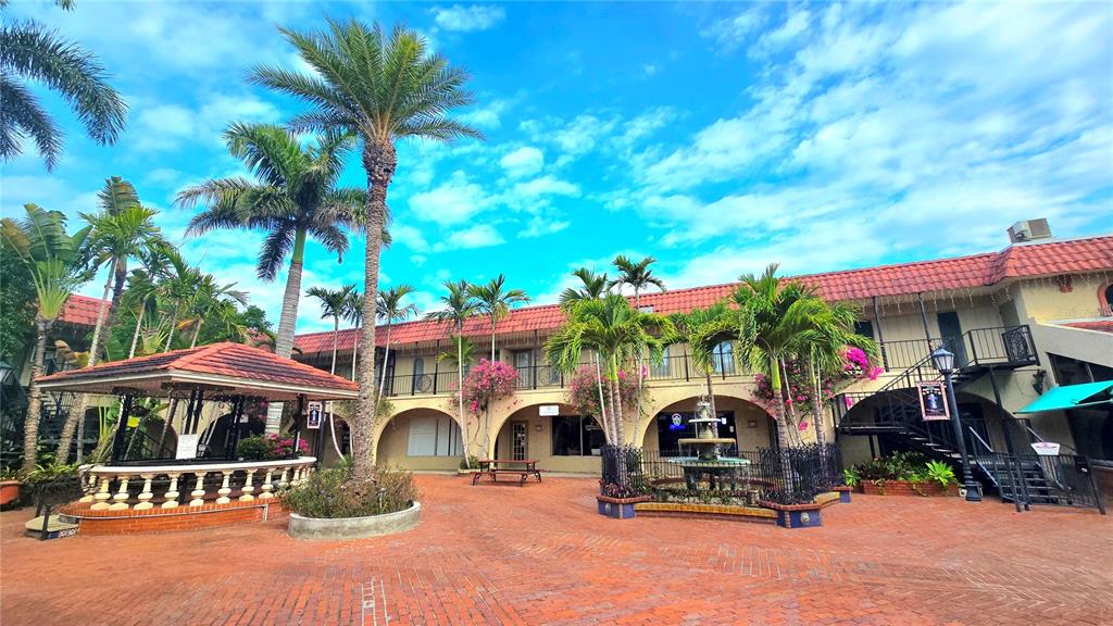 A brick courtyard features a gazebo, a central fountain, and palm trees in front of buildings — 530 US-41-BYP UNIT 17B, VENICE, FL