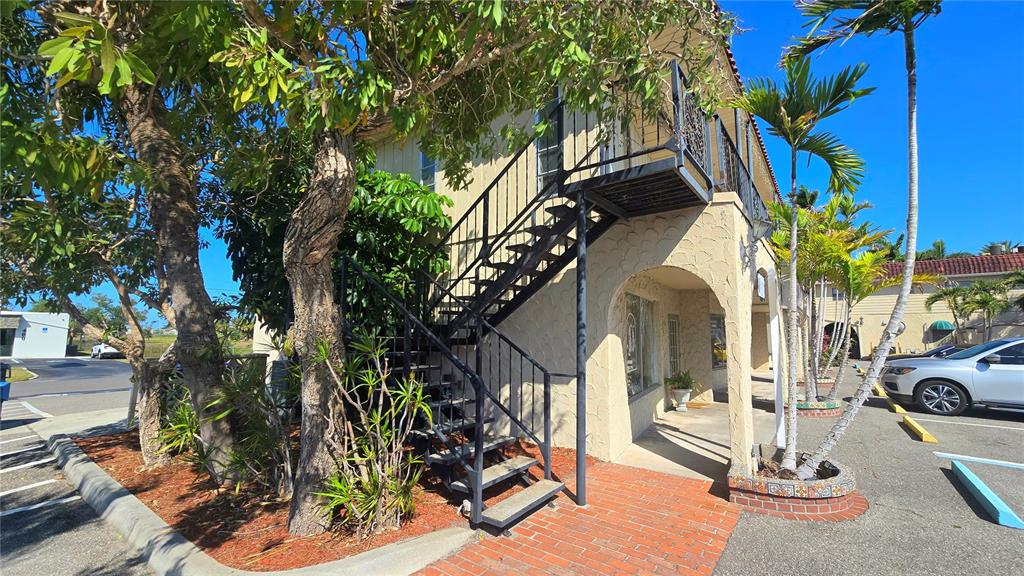 An exterior view of a two-story building featuring an outdoor metal staircase and palm trees — 530 US-41-BYP UNIT 17B, VENICE, FL