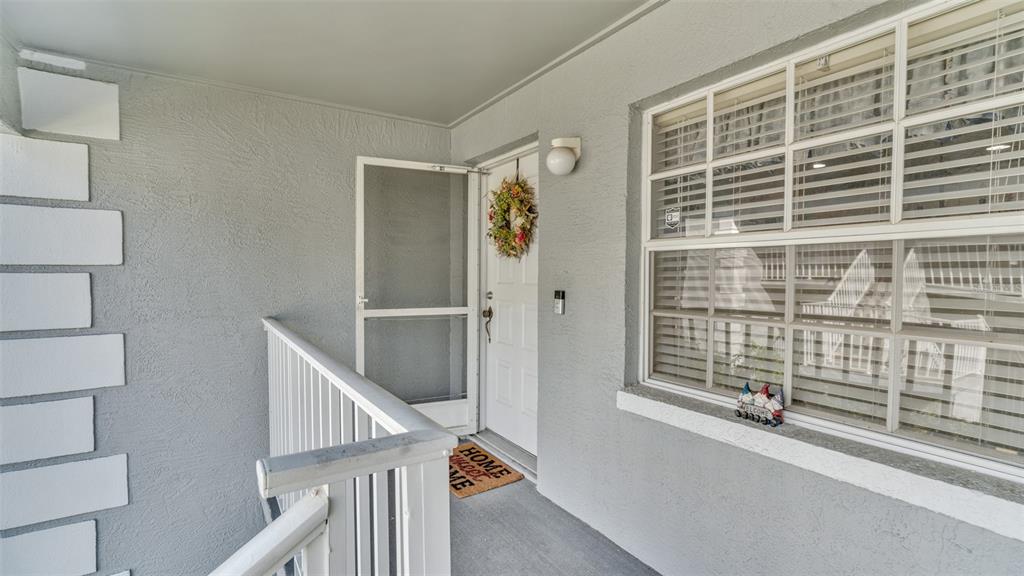 A gray exterior entryway features a white door with a wreath and a window — 12133 SPARTAN WAY UNIT 204, HUDSON, FL