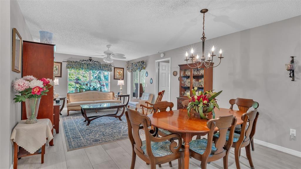 A dining area with a wooden table and chairs opens into a living room space — 12133 SPARTAN WAY UNIT 204, HUDSON, FL