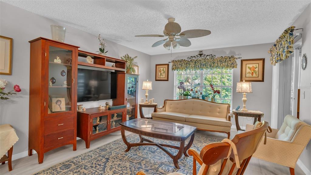 A living room features a wooden entertainment center, a beige sofa, and a patterned rug — 12133 SPARTAN WAY UNIT 204, HUDSON, FL