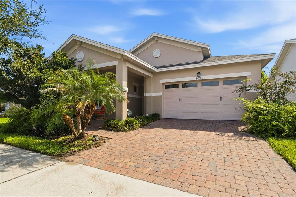 A single-story house with a beige exterior, a two-car garage, and a brick paver driveway — 5023 SUNFALLS AVENUE, ST CLOUD, FL