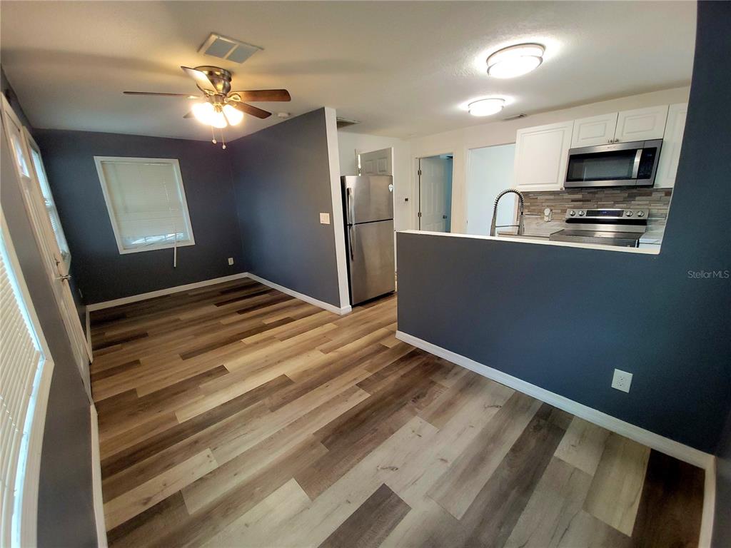 A dining area with wood-look flooring opens to a kitchen with stainless steel appliances — 3532 38TH AVENUE N, ST PETERSBURG, FL