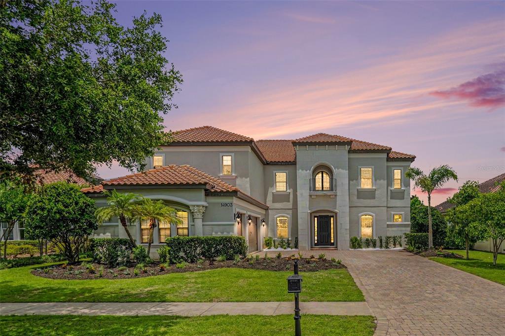 A two-story Mediterranean-style house with a tile roof and a paved driveway at sunset — 14903 OLD TOM MORRIS COURT, TAMPA, FL