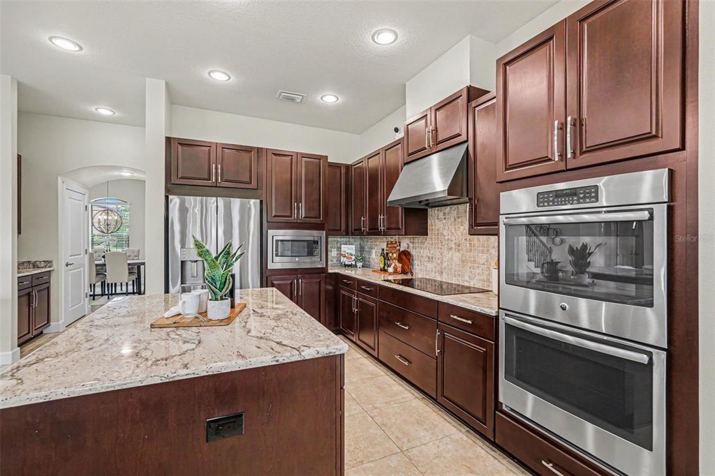 A kitchen features dark wood cabinets, stainless steel appliances, and a granite-topped island — 14903 OLD TOM MORRIS COURT, TAMPA, FL