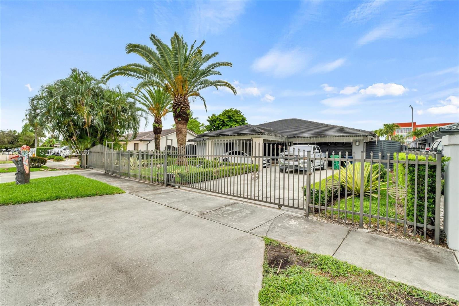 A single-story house with a gated driveway, palm trees, and a gray metal fence — 344 NW 136th Pl # B, Miami FL 33182, MIAMI, FL
