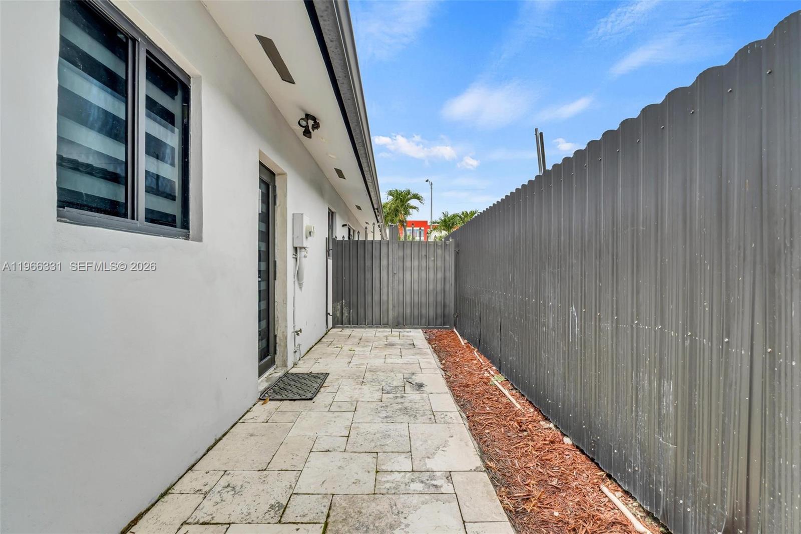 A paved side yard features a white exterior wall, a metal fence, and a gate — 344 NW 136th Pl # B, Miami FL 33182, MIAMI, FL